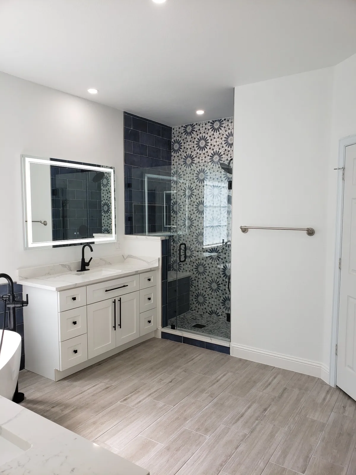 Bathroom after remodel with navy tile walk-in shower and black fixtures