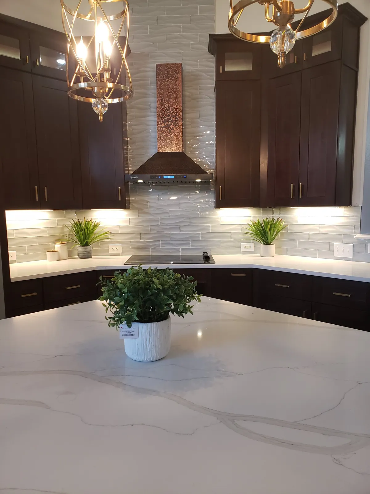 Kitchen after remodel with espresso cabinets, wave-tile backsplash and pendant lighting